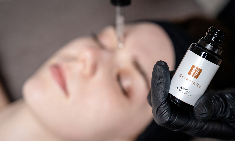 Serumflasche „FH Skincare Renew“ wird mit Handschuh gehalten und Serum wird mit Pipette auf Gesicht aufgetragen.