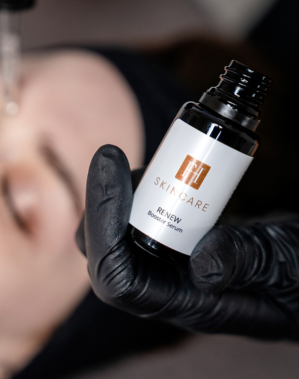 Serumflasche „FH Skincare Renew“ wird mit Handschuh gehalten.