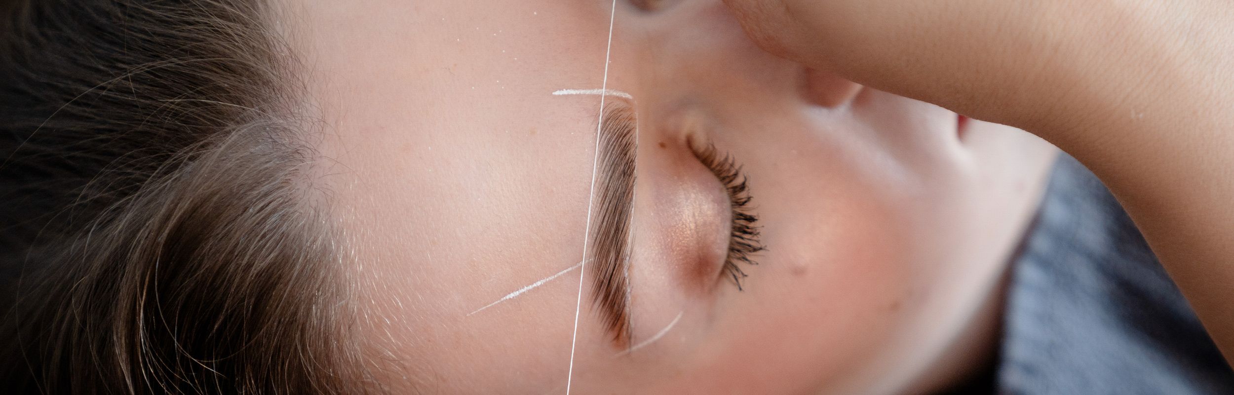 Nahaufnahme: Augenbrauen werden mit Stift nachgezeichnet.