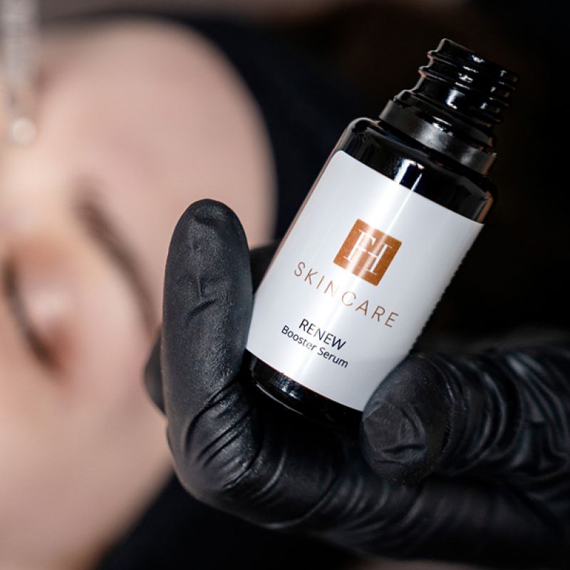 Serumflasche „FH Skincare Renew“ wird mit Handschuh gehalten.